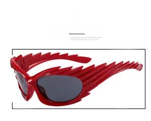 Detail close-up of red wing-shaped avant-garde sunglasses with dark tinted lenses