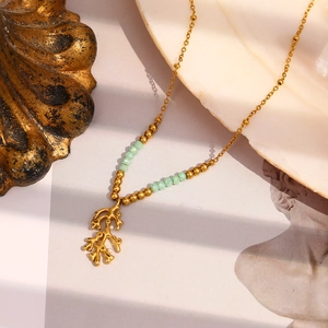 Detailed view of golden branch necklace with light green beads and coral-shaped pendant
