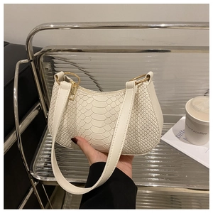 Close-up of white crocodile pattern baguette bag with stylish gold circular metal hardware