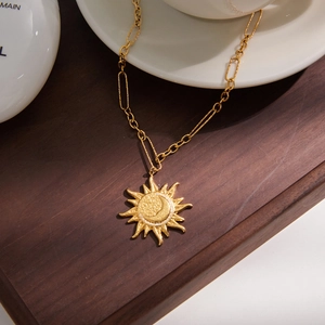 Detailed shot of golden sun and moon pendant with mixed-link chain in bohemian style