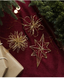 Close-up of glittery gold star and flower ornaments on festive red velvet background