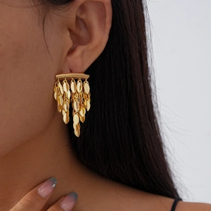 Detailed close-up of golden leaf tassel earrings with textured metallic finish on ear