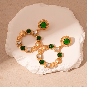 Detailed macro view of vintage gold ring earrings with green resin and square crystals