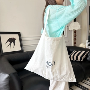 Detail of white nylon tote bag with navy blue lettering print on the fabric