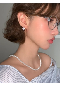 Close-up of pearl necklace and sparkling star-shaped stud earrings worn by a model
