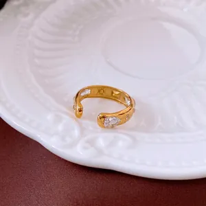 Minimalist gold geometric open ring with sparkling teardrop zircons on a ceramic tray