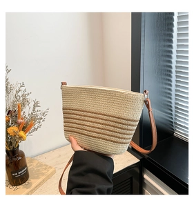 Detailed view of hand-held straw woven bucket bag with khaki and beige stripes