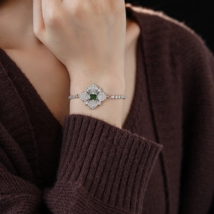 Detail of silver floral bracelet with emerald green stone and pavé gems on wrist