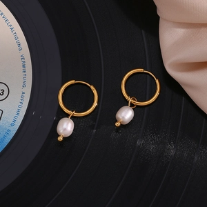 Macro view of 18K gold plated hoop earrings with baroque freshwater pearls on silk