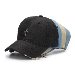 Detail of denim baseball cap with metallic cross emblem and gothic punk pendants