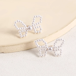 Detail of handmade butterfly earrings woven with vintage imitation pearls for women