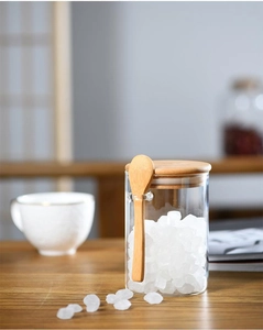 Detail of glass storage jar with wooden lid and spoon filled with white crystals