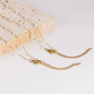 Elegant gold pearl necklace with adjustable lobster clasp on textured stone background