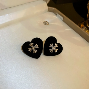 Detailed macro shot of black flocked heart earrings featuring a silver cross metal inlay