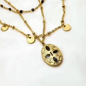 Layered gold necklace with black beads, small discs, and a vintage oval pendant
