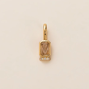 Macro detail of gold pendant featuring a large rectangle cut stone and round accents