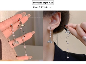 Detail of asymmetric long drop earrings with silver metal, pearls and crystal fishtails