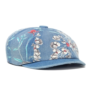 Detailed close-up of retro floral prints on light blue denim fabric of a beret hat