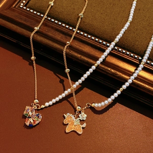 Detail of 18k gold plated pearl necklace with colorful zircon heart and pony pendants