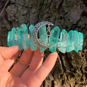 Detail of teal raw crystal crown with silver moon and star pendant on tree bark