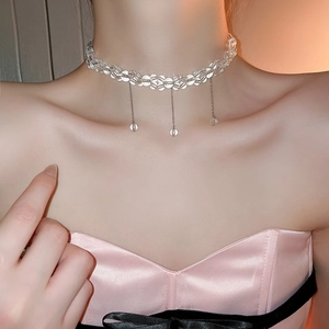 Close-up of sparkling clear beaded choker necklace with metallic tassel pendants on neck