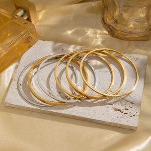 Minimalistische geometrische stapelbare Armreifen in Gold und Silber auf edlem Stein