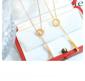 Detail of 18k gold and rose gold pendant necklaces with ring and bar charms in a red box