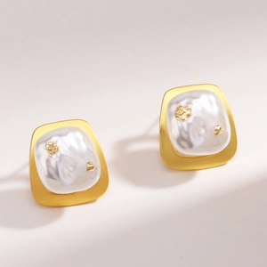 Détail de boucles d'oreilles carrées en or 18k avec perle et incrustation de dorure