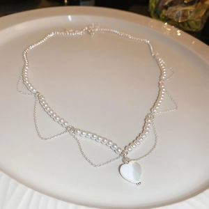 Détail d'un collier de perles vintage avec pendentif en forme de cœur sur céramique