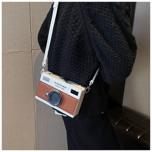 Detail of white and brown vintage camera cross-body bag with lens decoration and strap