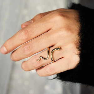 Close-up of golden snake-shaped adjustable open ring on model's index finger