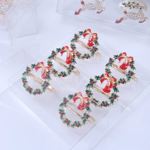 Detail view of six golden Christmas wreath napkin rings with green enamel and rhinestones