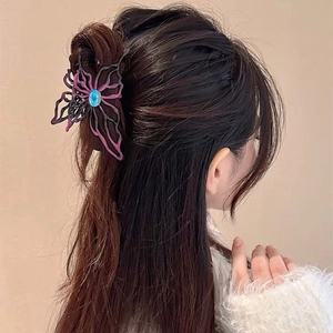 Detailed side view of a large butterfly hair claw with purple accents and a blue gemstone