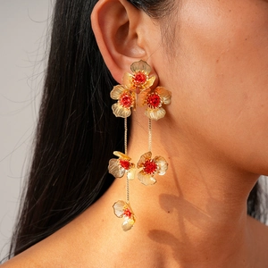 Boucles d'oreilles pendantes à pampilles dorées et fleurs rouges sur un mannequin
