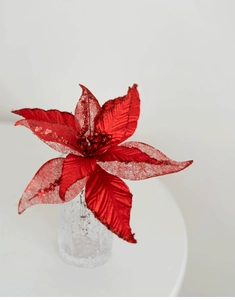 Gros plan de fleur de Noël rouge avec paillettes sur un support d'exposition