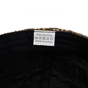 Detail view of the soft black cotton lining and wash care label inside a tweed baseball cap