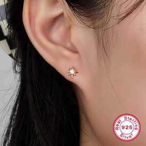 Elegant 925 sterling silver starburst stud earrings with sparkling crystals on model ear