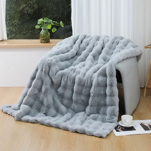 Detail shot of grey faux rabbit fur blanket with textured wavy patterns on a chair