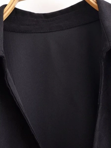Detail view of black fitted top with bow tie back and textured woven fabric on hanger