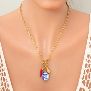 Gold stainless steel necklace with chili and porcelain pendants worn by a female model
