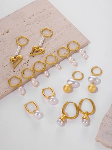 Detail of 18k gold plated fringe earrings with faux pearls on stone texture surface