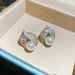 Detailed view of leaf-shaped gold stud earrings featuring small zircons and white pearls