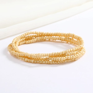 Detail of cream seed bead body chain showing multi-layered elastic wrap texture