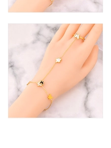 Elegant gold hand harness with white flower and butterfly motifs on a hand model