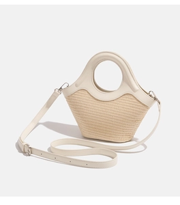 Detailed close-up of woven straw and smooth cream PU leather texture with round hollow handle