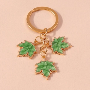Macro detail of three green ginkgo leaf pendants with gold-plated edges on a keychain