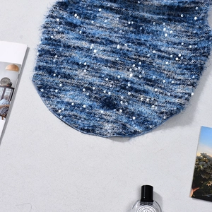 Macro detail of blue gradient knit fabric with shimmering silver sequins and plush texture