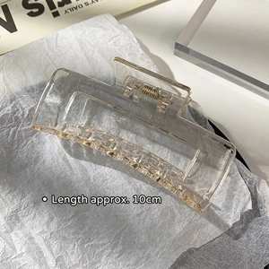 Detail view of a 10cm champagne acrylic hair claw clip with a golden metal spring