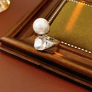 French luxury ring with large white pearl and square crystal on vintage wooden frame