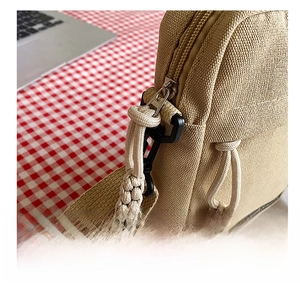 Macro detail of khaki canvas phone bag featuring a smooth metal zipper with cord puller